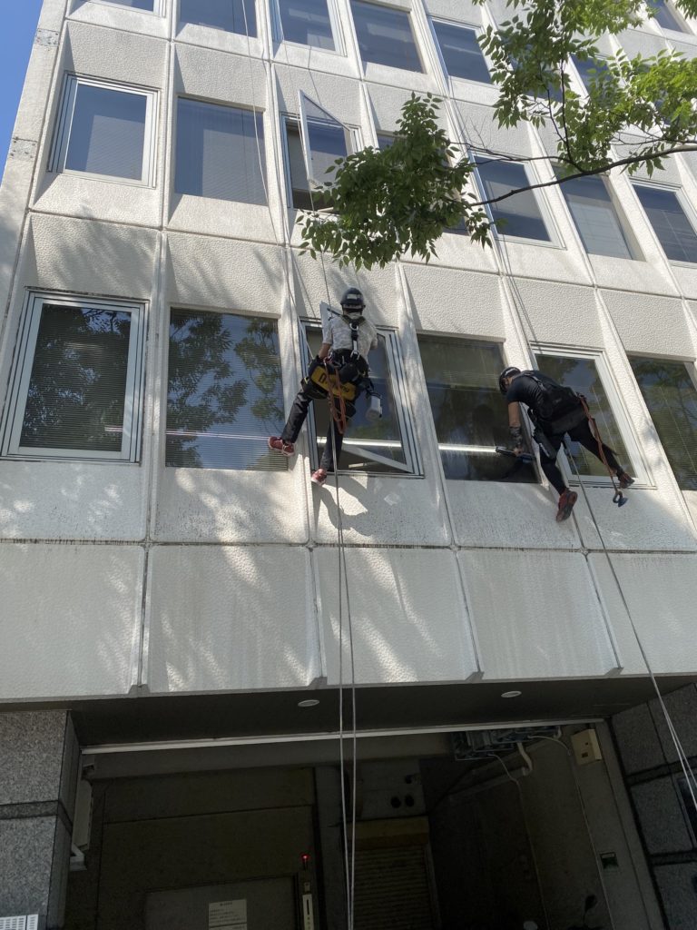 建物の窓を清掃するエステックの作業風景